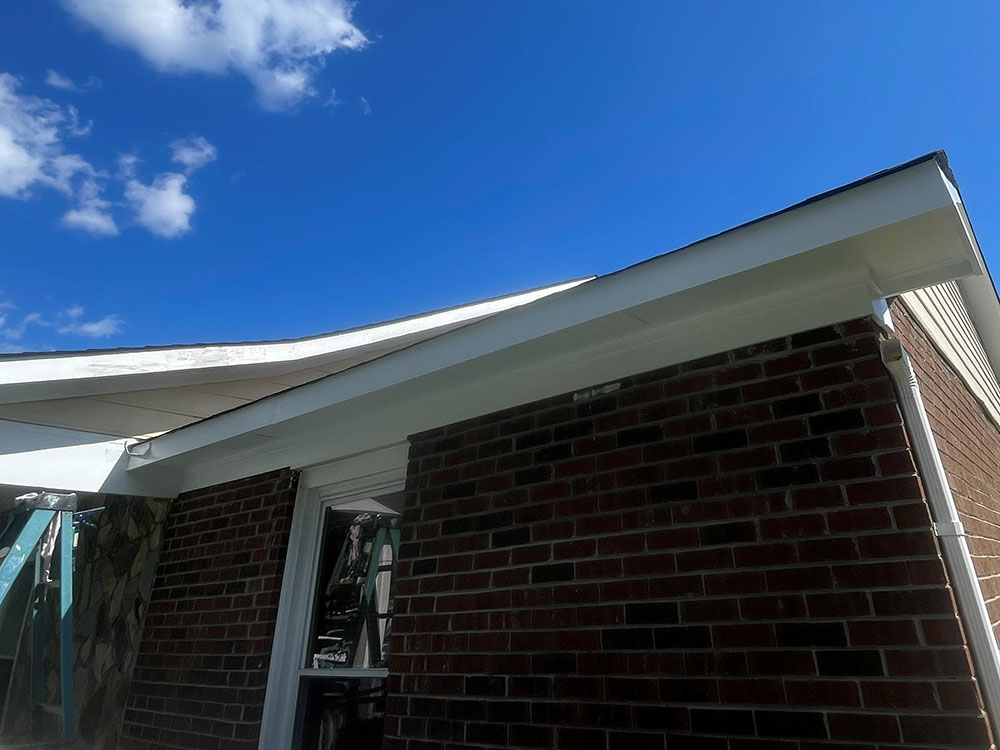 Freshly painted white soffit and fascia meeting brick wall
